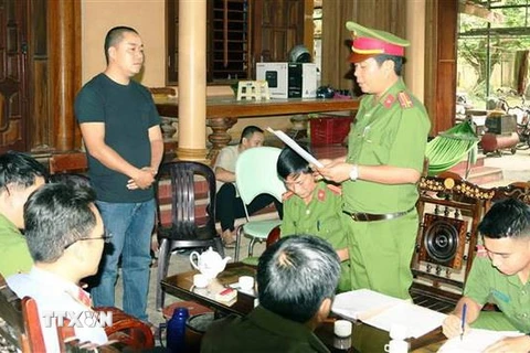 Lực lượng Công an tống đạt các quyết định khởi tố vụ án, khởi tố bị can và Lệnh tạm giam đối với Đinh Ngọc Tý. (Ảnh: Quang Văn/TTXVN phát)