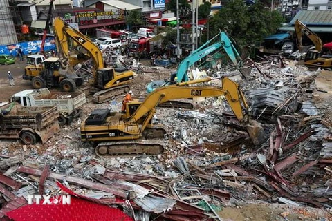 Nhân viên cứu hộ tìm kiếm nạn nhân trong vụ sập nhà cao tầng ở tỉnh Preah Sihanouk, miền Nam Campuchia. (Nguồn: AFP/TTXVN)