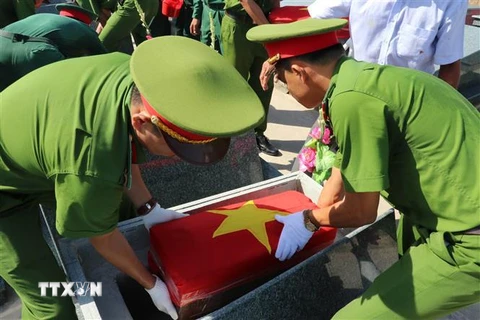 Hài cốt liệt sỹ hy sinh ở Campuchia được đưa về an táng tại nghĩa trang liệt sĩ Vĩnh Hưng, Tân Hưng. (Ảnh: Bùi Giang/TTXVN)