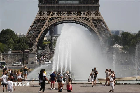 Người dân và khách du lịch giải nhiệt tại đài phun nước ở Paris, Pháp. (Ảnh: AFP/TTXVN)