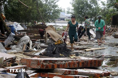 Người dân gom nhặt những gì còn sót lại từ căn nhà cũ đã bị sập ở xã Khánh Bình Tây, huyện Trần Văn Thời (Cà Mau). (Ảnh: Huỳnh Thế Anh/TTXVN)