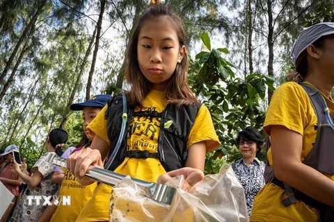 Cô bé Ralyn Satidtanasarn (thứ 2, phải) tham gia dọn rác tại khu vực Khung Bang Kachao, Bangkok, Thái Lan. (Ảnh: AFP/TTXVN)