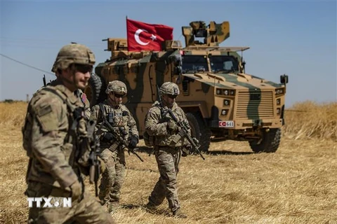 Binh sỹ Mỹ và xe quân sự của Thổ Nhĩ Kỳ tham gia cuộc tuần tra chung ở ngoại ô thị trấn Tal Abyad (Syria) giáp giới với Thổ Nhĩ Kỳ. (Ảnh: AFP/TTXVN)
