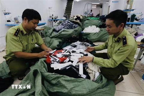 Lực lượng chức năng kiểm tra số hàng may mặc nhập khẩu được thay thế bằng nhãn mác IFU. (Ảnh: Trần Việt/TTXVN)