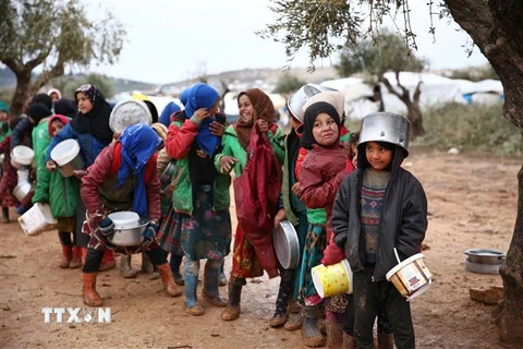 Trẻ em xếp hàng nhận thực phẩm cứu trợ tại một trại tị nạn ở tỉnh Aleppo, Syria. (Ảnh: AFP/TTXVN)
