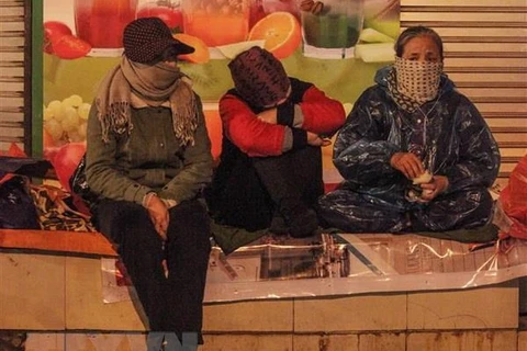 Người lao động co ro trong giá lạnh trên phố Tràng Thi, quận Hoàn Kiếm. (Ảnh: Minh Hoàng/TTXVN phát)
