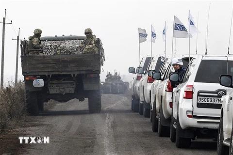 Các quan sát viên Tổ chức An ninh và Hợp tác châu Âu (OSCE) (phải) giám sát việc rút quân của các lực lượng Ukraine ở vùng Donetsk ngày 9/11. (Ảnh: AFP/TTXVN)