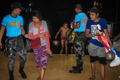Cảnh sát hỗ trợ người dân đến một trung tâm sơ tán khi cơn bão Phanfone đổ bộ tại Borongan, tỉnh Đông Samar, miền Trung Philippines. (Nguồn: AFP)