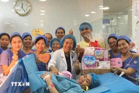 Ban giám đốc, êkíp trực đêm tại Bệnh viện Từ Dũ tặng quà cho sản phụ sinh con đầu tiên trong năm 2020. (Ảnh: Đinh Hằng/TTXVN)
