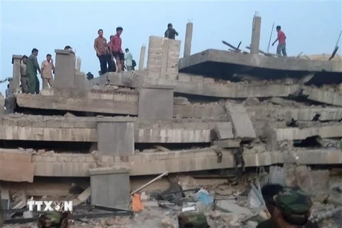 Lực lượng cứu hộ tìm kiếm nạn nhân dưới đống đổ nát của công trình đang thi công bị đổ sập. (Ảnh: AFP/TTXVN)