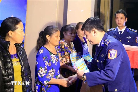 Thượng tá Lê Huy, Phó Chính ủy Bộ Tư lệnh vùng Cảnh sát biển 1, trao quà cho các gia đình chính sách trên huyện đảo Bạch Long Vĩ. (Ảnh: An Đăng/TTXVN)