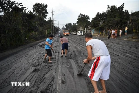 Người dân dọn tro bụi phun trào từ núi lửa Taal ở thị trấn Tanauan, tỉnh Batangas, Philippines. (Ảnh: AFP/TTXVN)