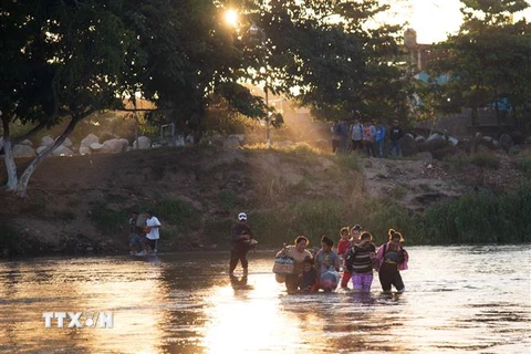 Người di cư vượt sông Suchiate từ Tecun Uman, Guatemala sang Mexico ngày 18/1. (Ảnh: AFP/TTXVN)