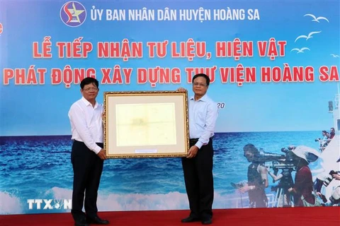 Các tổ chức, cá nhân trao tặng các tư liệu, hiện vật cho Chủ tịch Ủy ban Nhân dân huyện Hoàng Sa Võ ngọc Đồng (bên phải) tại buổi tiếp nhận. (Ảnh: Trần Lê Lâm/TTXVN)