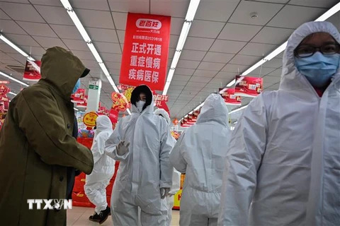 Nhân viên mặc quần áo bảo hộ và khẩu trang phòng chống dịch bệnh viêm phổi lạ do nhiễm virus corona phục vụ khách hàng tại một nhà thuốc ở Vũ Hán, Trung Quốc. (Ảnh: AFP/TTXVN)
