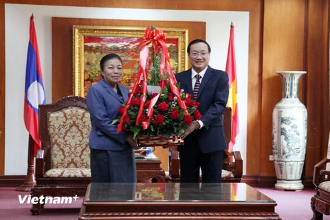 Bà Sounthone Sayachak trao lẵng hoa chúc mừng 90 năm ngày thành lập Đảng Cộng sản Việt Nam cho Đại sứ Việt Nam tại Lào Nguyễn Bá Hùng. (Ảnh: Phạm Kiên/Vietnam+)