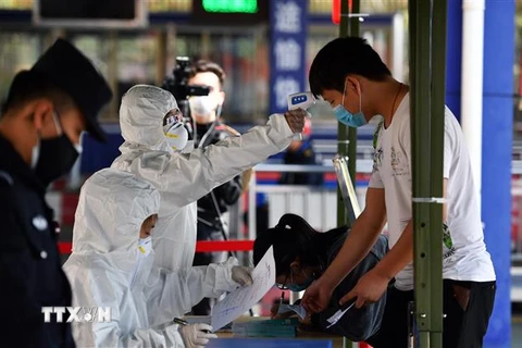 hân viên y tế kiểm tra thân nhiệt cho người dân tại thành phố Trạm Giang, tỉnh Quảng Đông, Trung Quốc. (Ảnh: THX/TTXVN)