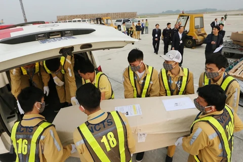 Nhân viên sân bay quốc tế Nội Bài vận chuyển thi thể các nạn nhân lên ôtô để đưa về quê nhà. (Ảnh: Lâm Khánh/TTXVN)