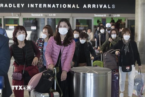 Hành khách đeo khẩu trang phòng lây nhiễm virus corona tại sân bay quốc tế Los Angeles ở California, Mỹ. (Ảnh: AFP/TTXVN)