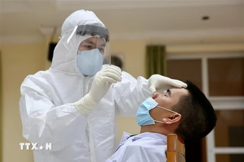 Nhân viên y tế tiến hành lấy mẫu bệnh phẩm từ mũi của người nghi nhiễm để xét nghiệm SARS-CoV-2. (Ảnh: Dương Giang/TTXVN)