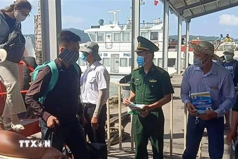 Đoàn viên thanh niên Bộ đội Biên phòng tỉnh phát khẩu trang miễn phí cho du khách từ huyện đảo Phú Quốc vào thành phố Rạch Giá bằng tàu biển. (Ảnh: Lê Sen/TTXVN)