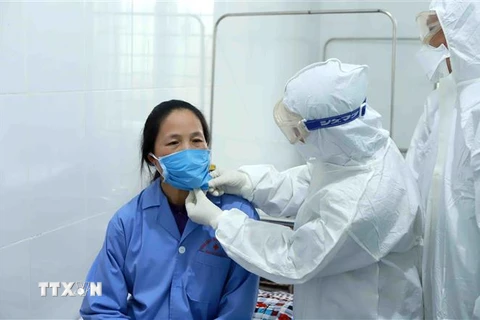 Bác sỹ Đội cơ động Bệnh viện Bạch Mai (Hà Nội) thăm khám bệnh nhân dương tính với virus corona tại Trung tâm y tế huyện Bình Xuyên (Vĩnh Phúc). (Ảnh: Hoàng Hùng/TTXVN)