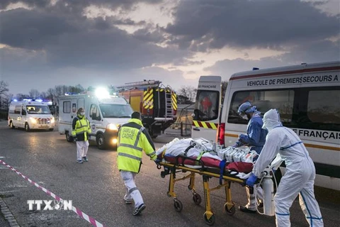 Lực lượng y tế khẩn cấp chuyển bệnh nhân nhiễm COVID-19 từ bệnh viện ở Mulhouse lên xe cứu thương để sơ tán tới các bệnh viện ở phía Tây nước Pháp. (Ảnh: AFP/TTXVN)