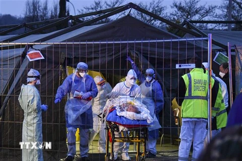 Nhân viên y tế chuyển bệnh nhân nhiễm COVID-19 từ một bệnh viện quân y tới bệnh viện ở Mulhouse, miền Đông Pháp. (Ảnh: AFP/TTXVN)