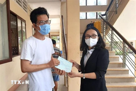 Phó Giám đốc Sở Y tế tỉnh Vĩnh Long Hồ Thị Thu Hằng trao giấy chứng nhận hoàn thành cách ly cho người dân. (Ảnh: Lê Thúy Hằng/TTXVN)