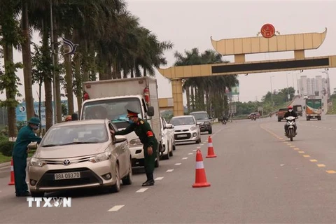 Lực lượng chức năng kiểm tra thân nhiệt cho người tham gia giao thông tại điểm cầu Đại Phúc, thành phố Bắc Ninh. (Ảnh: Thanh Thương/TTXVN)