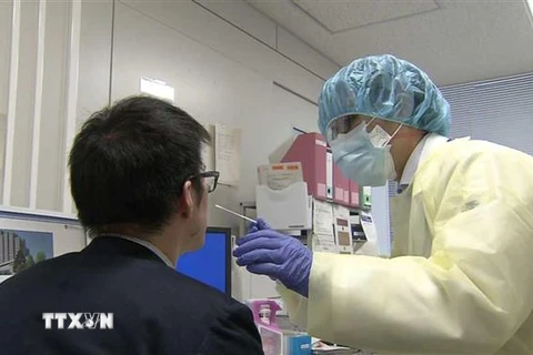 Nhân viên y tế lấy mẫu xét nghiệm COVID-19. (Ảnh: NHK/TTXVN)