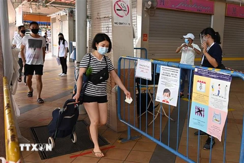 Người dân đeo khẩu trang và thực hiện giãn cách xã hội phòng lây nhiễm dịch COVID-19 tại một chợ ở Singapore. (Ảnh: AFP/TTXVN)
