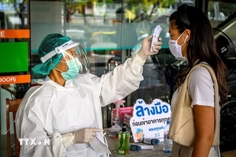 Nhân viên y tế kiểm tra thân nhiệt phòng lây nhiễm COVID-19 tại Bangkok,Thái Lan. (Ảnh: AFP/TTXVN)