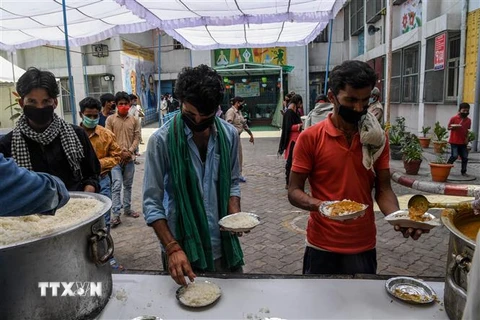 Người lao động nhập cư xếp hàng nhận bữa ăn miễn phí ở New Delhi, Ấn Đô. (Ảnh: AFP/TTXVN)