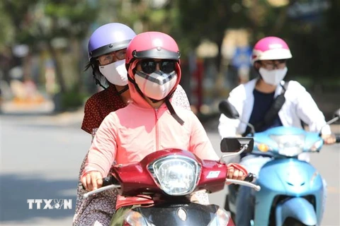 Người dân đeo khẩu trang mặc đồ tránh nắng khi tham gia giao thông. (Ảnh: Thành Đạt/TTXVN)