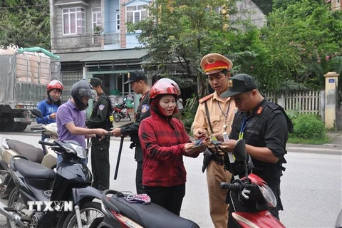Lực lượng chức năng kiểm tra giấy phép lái xe, đăng ký xe đối với người điều khiển phương tiện xe môtô. (Ảnh: TTXVN phát)