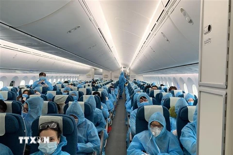 Tất cả hành khách được phát và phải mặc đồ bảo hộ trong suốt chuyến bay từ Vương quốc Anh về Việt Nam. (Ảnh: TTXVN phát)