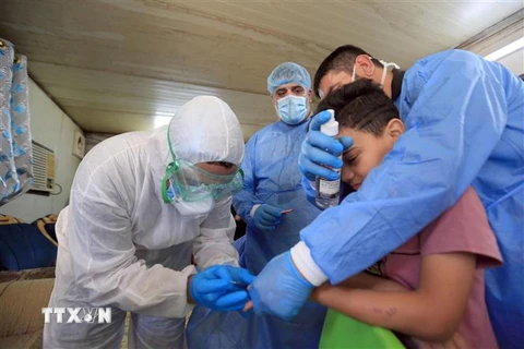 Nhân viên y tế lấy mẫu xét nghiệm COVID-19 cho một em nhỏ tại Baghdad, Iraq. (Ảnh: THX/TTXVN)