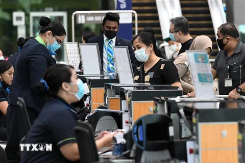 Hành khách làm thủ tục tại sân bay quốc tế Changi ở Singapore. (Ảnh: AFP/TTXVN)