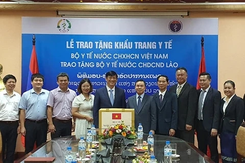 Ông Nguyễn Thanh Long trao khẩu trang (tượng trưng) tặng Đại sứ Lào tại Việt Nam Sengphet Houngboungnuang. (Nguồn: qdnd.vn)