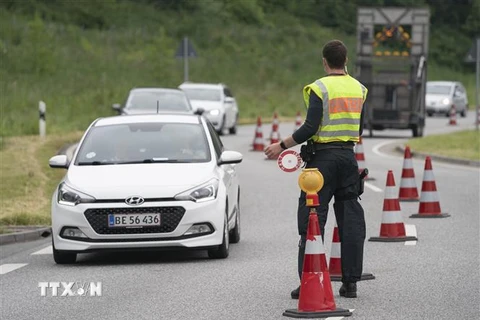 Cảnh sát Đức điều khiển các phương tiện giao thông đi qua cửa khẩu Krusaa-Flensburg. (Ảnh: AFP/TTXVN)