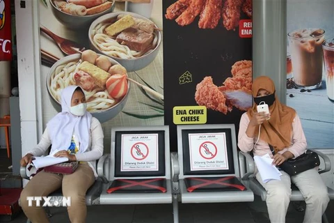 Người dân đeo khẩu trang và thực hiện giãn cách xã hội phòng lây nhiễm COVID-19 tại Jakarta, Indonesia. (Ảnh: THX/TTXVN)