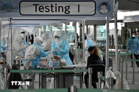 Nhân viên y tế lấy mẫu dịch xét nghiệm COVID-19 cho hành khách tại sân bay quốc tế Incheon, Hàn Quốc. (Ảnh: AFP/TTXVN)
