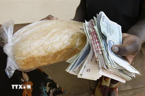 Người dân trả tiền để mua bánh mì tại Harare, Zimbabwe. (Ảnh: AFP/TTXVN)