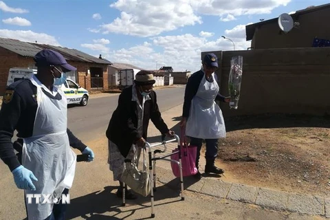 Cảnh sát giúp đỡ một người già trên đường đi mua thực phẩm. (Ảnh: Phi Hùng/TTXVN)