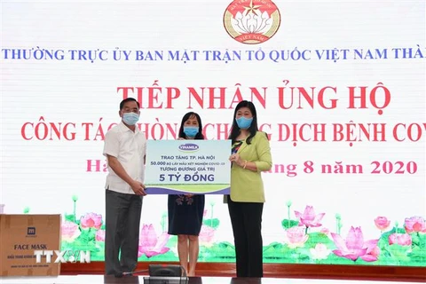 Chủ tịch Ủy ban Mặt trận Tổ quốc Việt Nam thành phố Hà Nội Nguyễn Lan Hương cùng lãnh đạo Sở Y tế Hà Nội tiếp nhận hỗ trợ 50.000 bộ lấy mẫu xét nghiệm SARS-COV-2. (Ảnh: TTXVN phát)