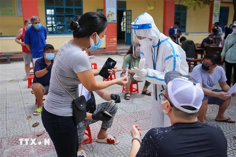 Nhân viên y tế phát lọ đựng mẫu xét nghiệm cho người nước ngoài tại quận Sơn Trà (Đà Nẵng). (Ảnh: Trần Lê Lâm/TTXVN)