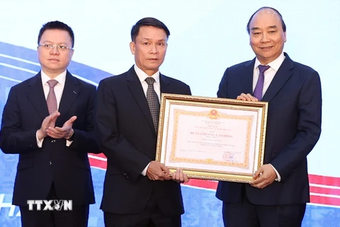 Thủ tướng Nguyễn Xuân Phúc, Chủ tịch Hội đồng Thi đua-Khen thưởng Trung ương, trao tặng Huân chương Lao động hạng Nhất cho Thông tấn xã Việt Nam. (Ảnh: Thống Nhất/TTXVN)