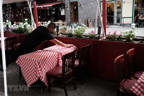 Nhân viên sửa soạn lại bàn ghế tại một nhà hàng ở New York, Mỹ. (Ảnh: AFP/TTXVN)