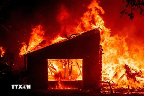 Một tòa nhà bốc cháy dữ dội do cháy rừng lan rộng tại St. Helena, bang California, Mỹ. (Ảnh: AFP/TTXVN)